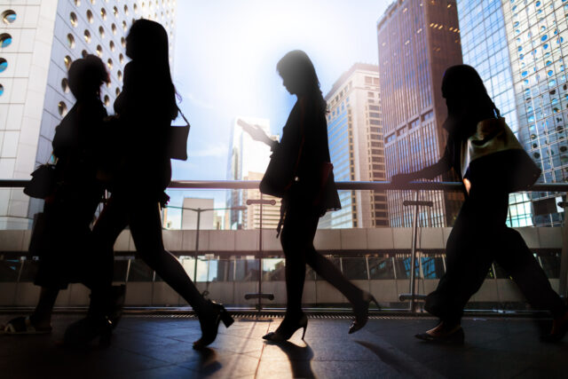 Blurred silhouettes of businesswomen walking. Depiction of a global Job market, and the benefits of knowing English.